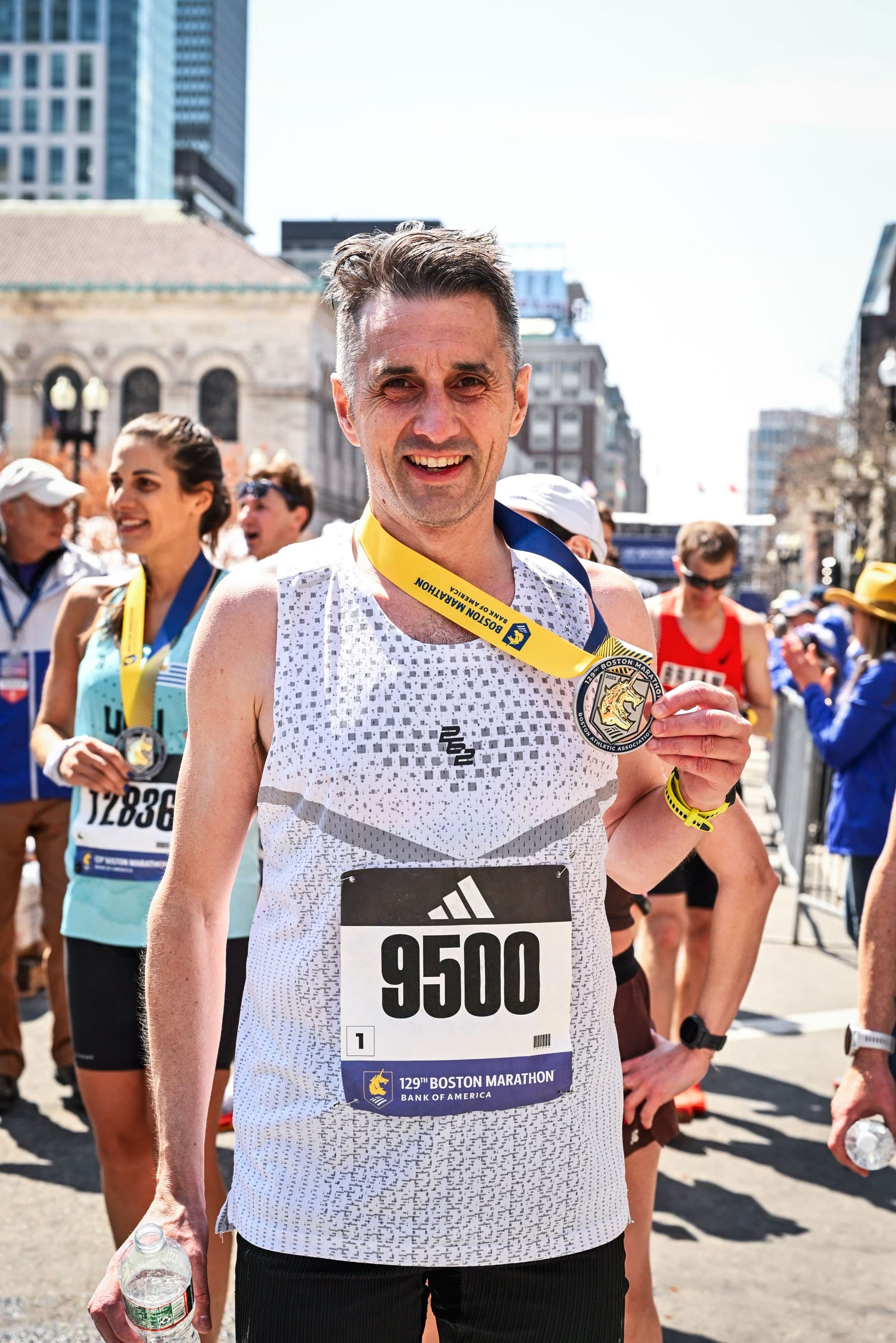 John McCurdy holding the 129th Boston Marathon medal on Boylston Street after finishing