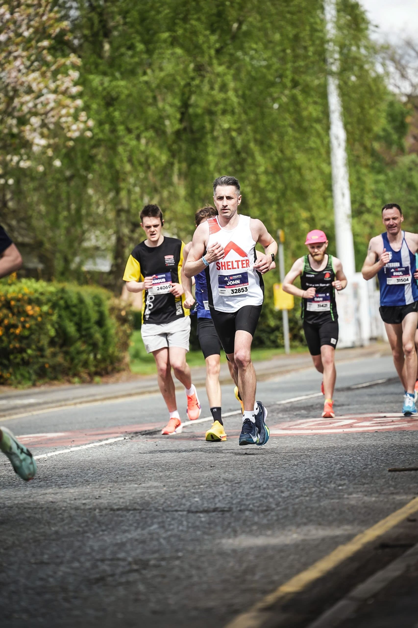 A runner leading a small group on the road during the Manchester Marathon